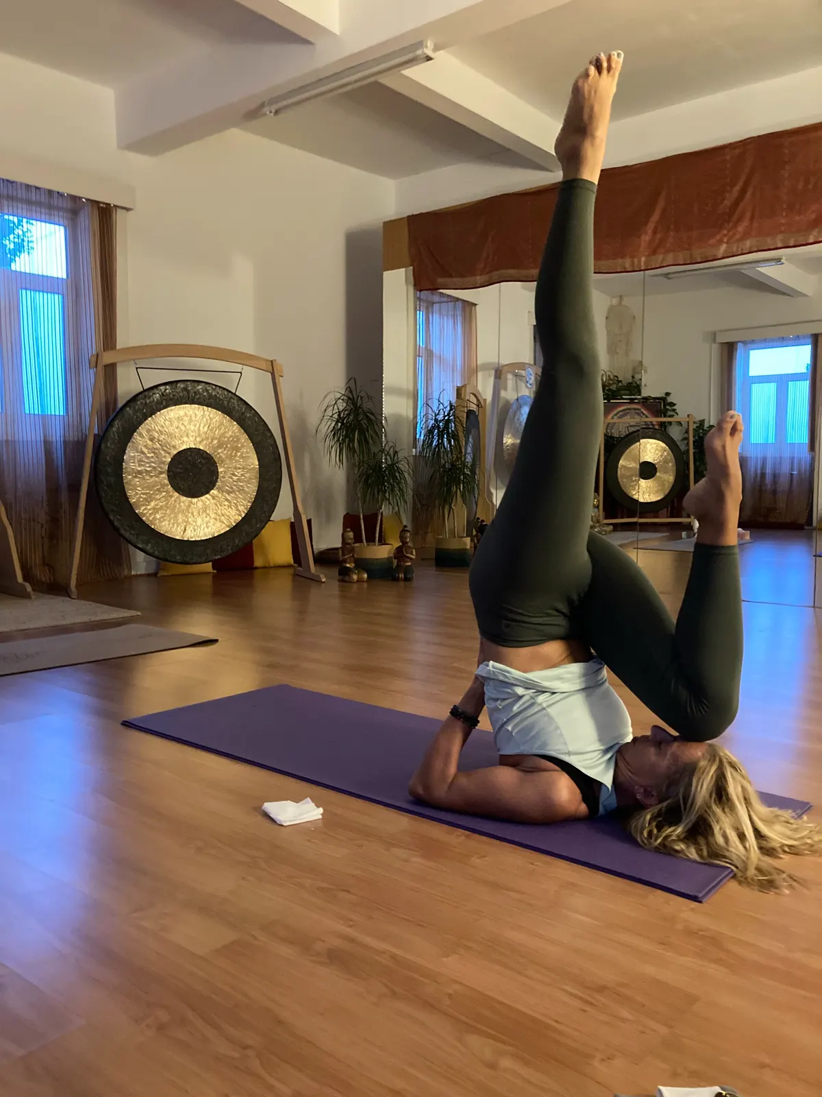 Aluna numa posição invertida na sala do Magnaluz, com gongos ao fundo