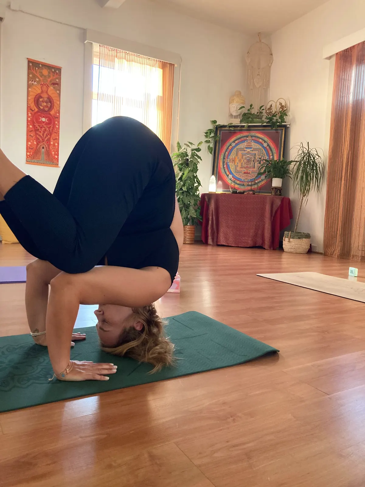 Aluna numa invertida na sala do Magnaluz, com o altar e as plantas ao fundo